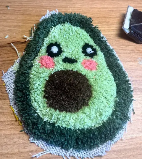 Dieselbe Avocado mitten im Carving: runde, scharf abgegrenzte Augen und Wangen, daneben liegt eine Schermaschine.