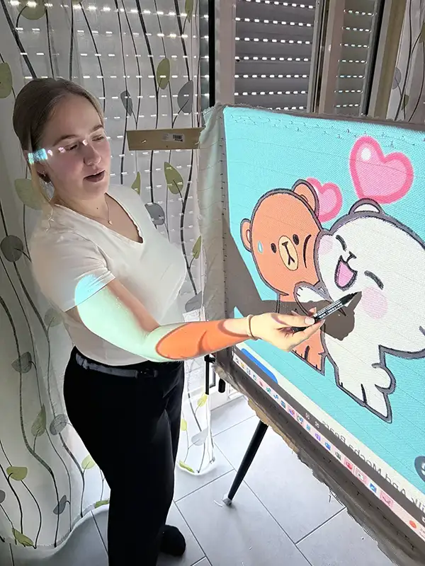 Mit Hilfe eines Projektors überträgt eine Teilnehmerin im Kurs ein Bärchen-Motiv auf Tufting-Gewebe.